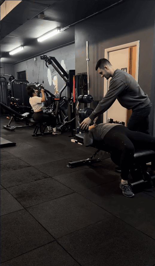 BAM Fitness coach spotting a client on the bench while another trains nearby during a small group session in Dumont, NJ