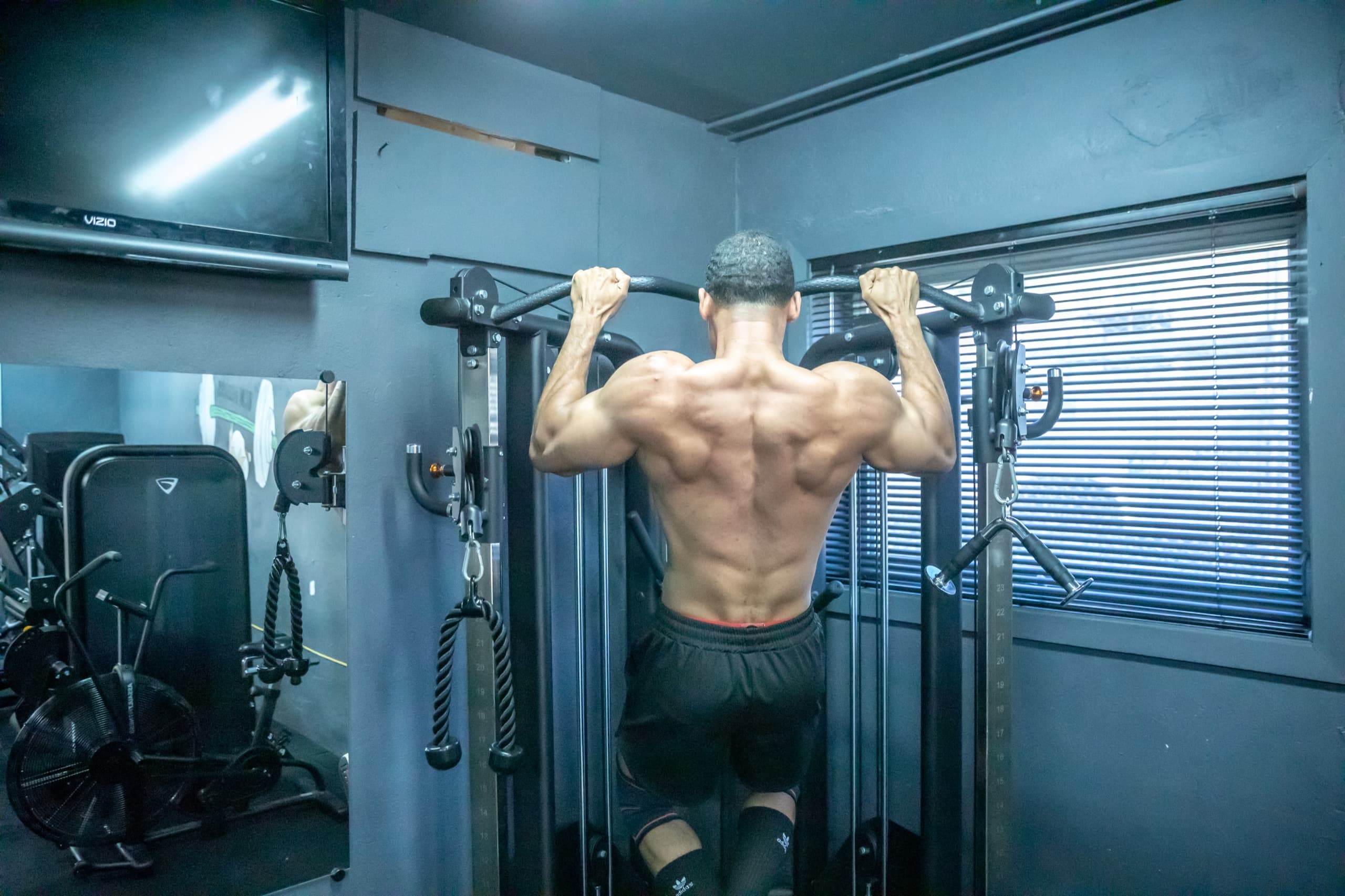 Client performing weighted pull-ups during a strength training session at BAM Fitness in Dumont, NJ