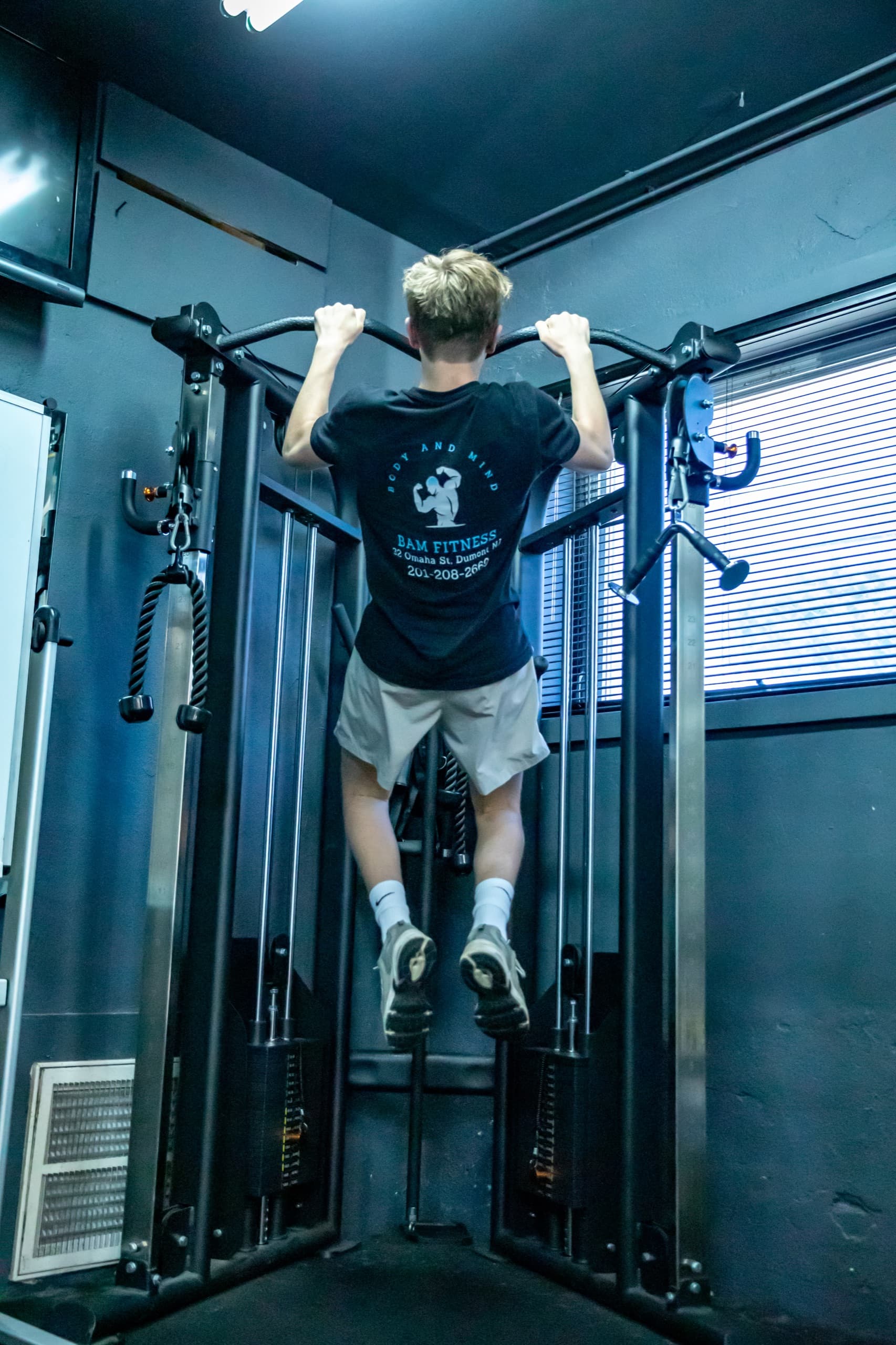 Client doing pull-ups in a BAM Fitness shirt during a personal training session in Dumont, NJ
